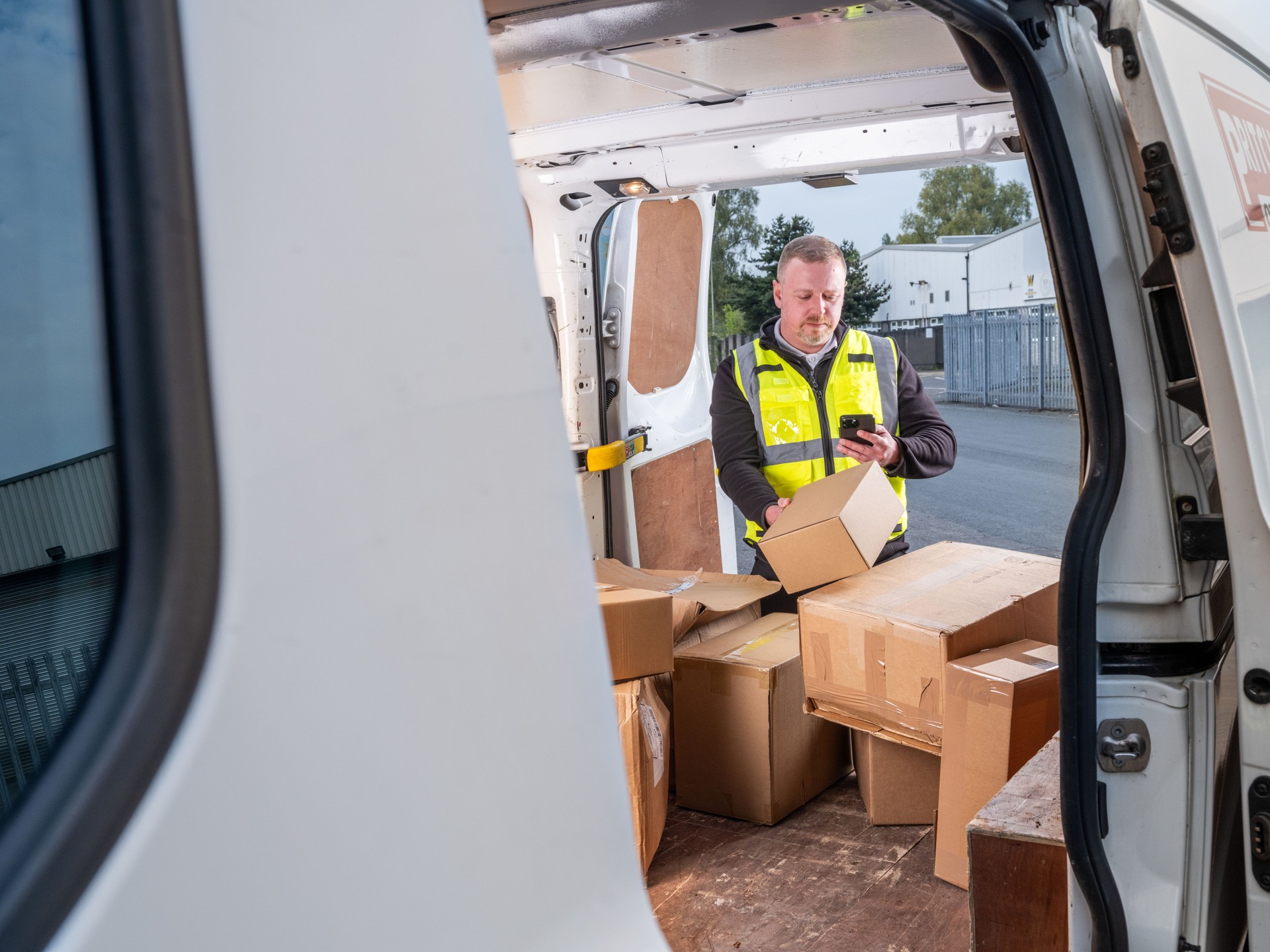 Delivery Driver Scanning Parcel with Phone in Van