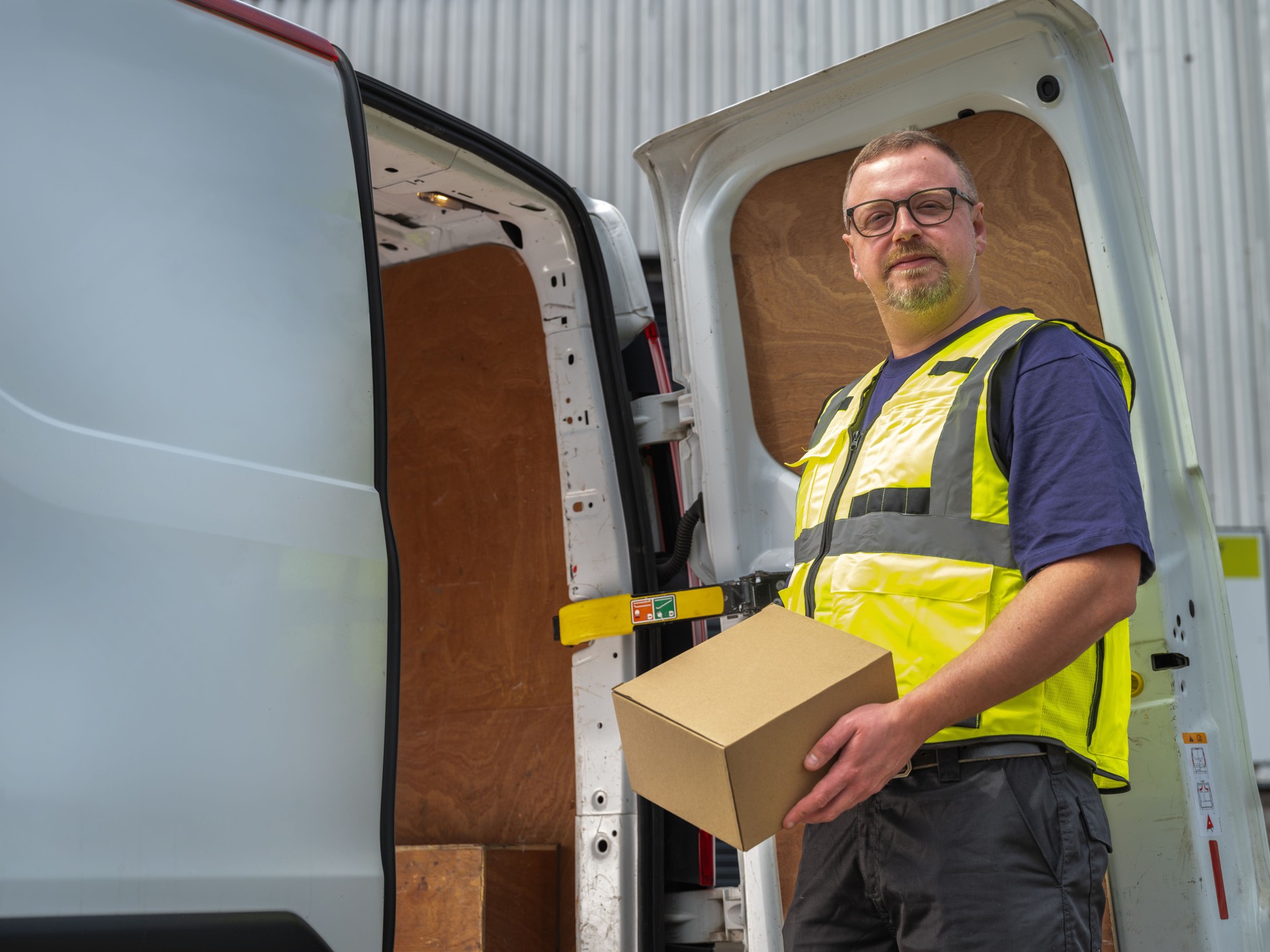 Van Driver with Parcel at Delivery Van Door